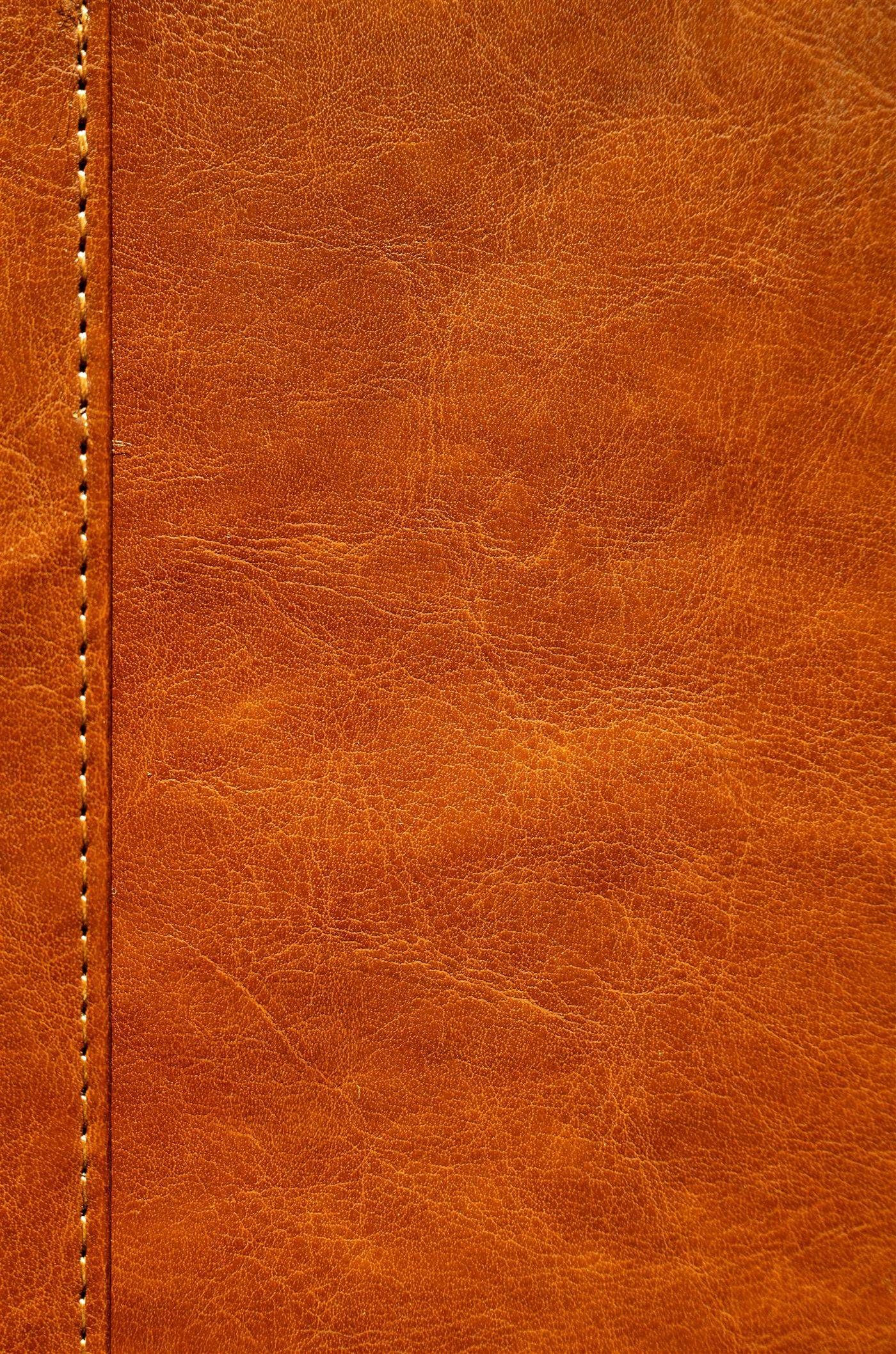 Hand-stitched seam running through warm cognac leather